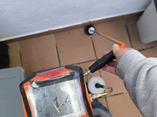 Detector electrónico de fugas apoyado sobre el pavimento durante una inspección