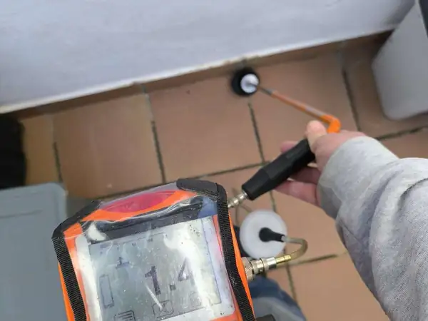 Detector electrónico de fugas apoyado sobre el pavimento durante una inspección